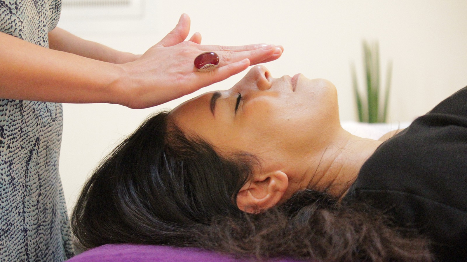 Hands resting gently above a client's forehead during a Reiki session
